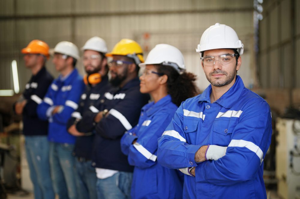 Young confident leader of team standing in front of factory workers